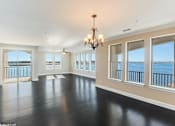 Thumbnail 16 of 25 - A large empty room with a chandelier and a view of the water.