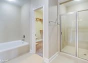 Thumbnail 25 of 25 - A white bathroom with a glass shower door and a bathtub.