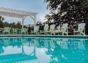 Thumbnail 9 of 25 - A pool with a white canopy and green chairs.