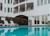 Thumbnail 8 of 25 - A white building with a pool in front.