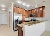Thumbnail 18 of 25 - A kitchen with brown cabinets and a marble countertop.