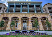 Thumbnail 32 of 36 - The Travis Leasing building is made of stone and has a green awning.