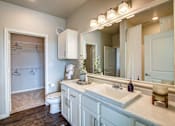 Thumbnail 3 of 36 - A bathroom with a toilet, sink, and mirror.