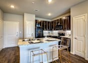 Thumbnail 4 of 36 - A kitchen with a white island and a black refrigerator.