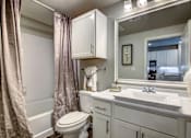 Thumbnail 11 of 36 - A white bathroom with a toilet, sink, and a mirror.