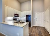 Thumbnail 12 of 36 - A kitchen with a granite countertop and white cabinets.