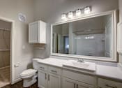 Thumbnail 13 of 36 - A bathroom with a toilet, sink, and mirror.