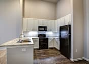 Thumbnail 14 of 36 - A kitchen with a granite countertop and white cabinets.