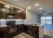 Thumbnail 19 of 36 - A kitchen with dark brown cabinets and black appliances.