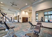Thumbnail 27 of 36 - A gym with a mirror, treadmill, and weights.