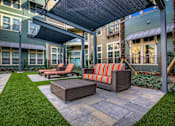 Thumbnail 22 of 36 - A patio with a couch and a table under a canopy.