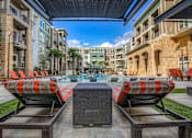 Thumbnail 21 of 36 - A patio with orange chairs and a table with a glass top.