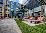 Thumbnail 23 of 36 - A patio area with a striped couch and a tree.