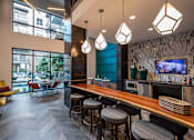 Thumbnail 5 of 30 - A modern bar area with a long wooden bar and stools.