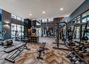 Thumbnail 3 of 30 - A gym with a variety of equipment including weights and machines.