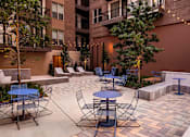Thumbnail 25 of 30 - A courtyard with tables and chairs surrounded by apartment buildings.
