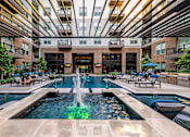 Thumbnail 23 of 30 - A large fountain in the middle of a pool surrounded by lounge chairs.