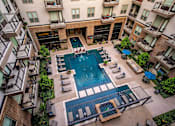 Thumbnail 22 of 30 - A large swimming pool surrounded by lounge chairs and balconies of apartment buildings.