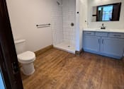 Thumbnail 8 of 14 - A bathroom with a toilet, sink, and wooden floor.