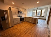 Thumbnail 7 of 14 - A kitchen with wooden floors and stainless steel appliances.