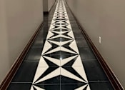 Thumbnail 11 of 14 - A long hallway with a black and white floor design.