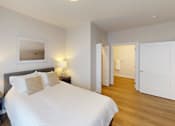 Thumbnail 14 of 27 - Bedroom with a large white bed and a wooden floor at The Landing Apartments, Indiana
