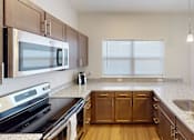 Thumbnail 12 of 27 - Kitchen with granite counter tops and wooden cabinets at The Landing Apartments, Indiana