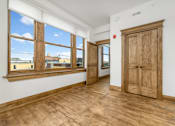 Thumbnail 14 of 14 - A room with wooden floors and a large window.