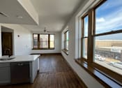 Thumbnail 6 of 14 - A kitchen with a dishwasher and a window overlooking a parking lot.