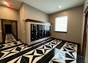 Thumbnail 2 of 14 - A hallway with a black and white tiled floor and a digital clock on the wall.