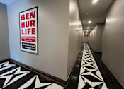 Thumbnail 1 of 14 - A hallway with a Ben Hur Life sign on the wall.