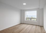 Thumbnail 24 of 25 - A room with a large window and wooden flooring.