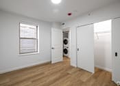Thumbnail 23 of 25 - A white room with a window and a door leading to a laundry room.