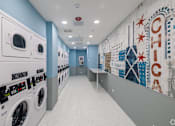 Thumbnail 8 of 25 - A laundromat with washers and dryers and a mural on the wall.