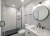 Thumbnail 25 of 25 - A white bathroom with a toilet, sink, and shower.