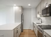 Thumbnail 15 of 25 - A modern kitchen with white countertops and stainless steel appliances.
