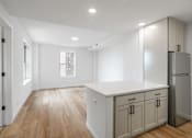 Thumbnail 16 of 25 - A kitchen with wooden floors and white walls.