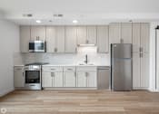 Thumbnail 17 of 25 - A modern kitchen with wooden floors and stainless steel appliances.