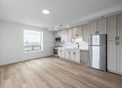 Thumbnail 18 of 25 - A kitchen with white cabinets and a wooden floor.