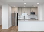 Thumbnail 22 of 25 - A modern kitchen with a stainless steel refrigerator and white countertops.
