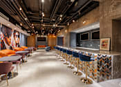 Thumbnail 10 of 25 - A long row of bar stools with a blue velvet barrier.