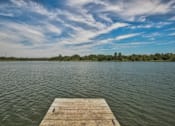 Thumbnail 44 of 46 - A wooden dock extends into a calm body of water under a blue sky with scattered clouds. at Standing Bear Lake, Omaha, Nebraska