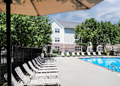 Thumbnail 7 of 46 - A pool with chairs and a building in the background. at Standing Bear Lake, Omaha