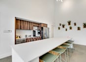 Thumbnail 24 of 36 - A white table with green chairs is in front of a wall with a picture of a kitchen.