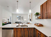 Thumbnail 2 of 36 - A modern kitchen with wooden cabinets and a stainless steel dishwasher.