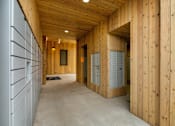 Thumbnail 31 of 36 - A long hallway with wooden walls and a concrete floor.