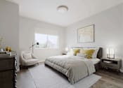 Thumbnail 12 of 36 - A bedroom with a large bed, a chair, and a nightstand.