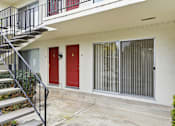 Thumbnail 99 of 133 - A white building with a red door and a black railing on the stairs.