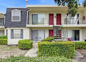 Thumbnail 108 of 133 - A white two-story apartment building with red doors and a red staircase.