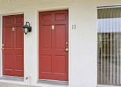 Thumbnail 101 of 133 - Two red doors with gold knobs and a lamp on the wall.